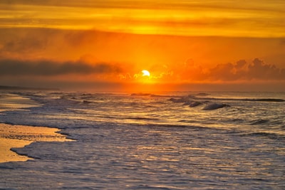 夕阳下海浪撞在岸上
